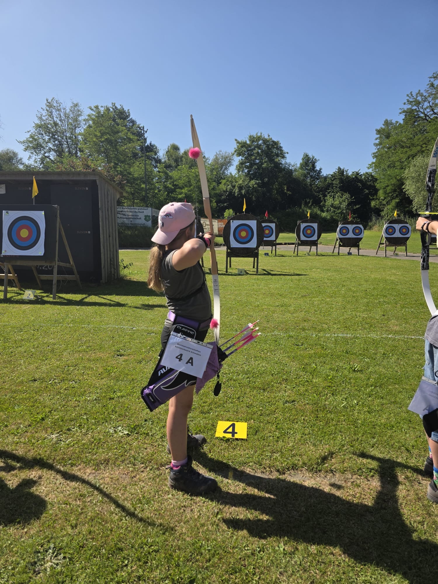 Mädchen zielt mit Recurve-Bogen auf WA-Scheiben