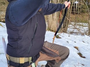 Bogenschütze zielt kniend mit Reiterbogen