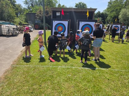 viele Kinder vor Zielscheiben im Bogensport