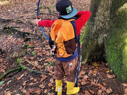 Kind zielt mit Kinderbogen